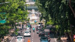 Suasana jalanan yang ramai dengan mobil dan sepeda motor di Surabaya, Indonesia. Kehidupan kota dan lalu lintas yang sibuk.