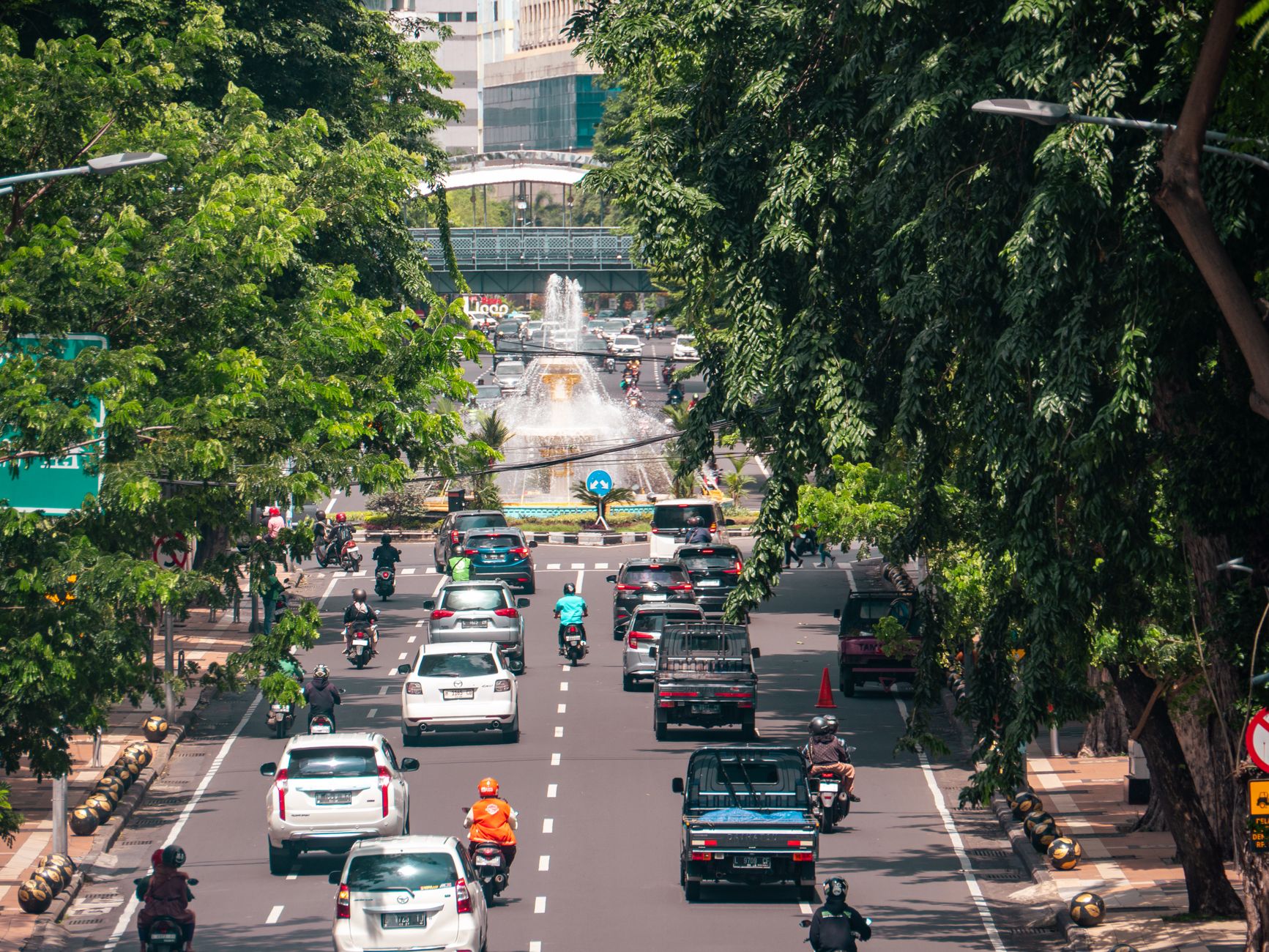Suasana jalanan yang ramai dengan mobil dan sepeda motor di Surabaya, Indonesia. Kehidupan kota dan lalu lintas yang sibuk.