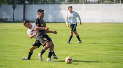 Pemain dalam pertandingan sepak bola yang intens, menunjukkan kerja sama tim dan keterampilan di lapangan hijau.
