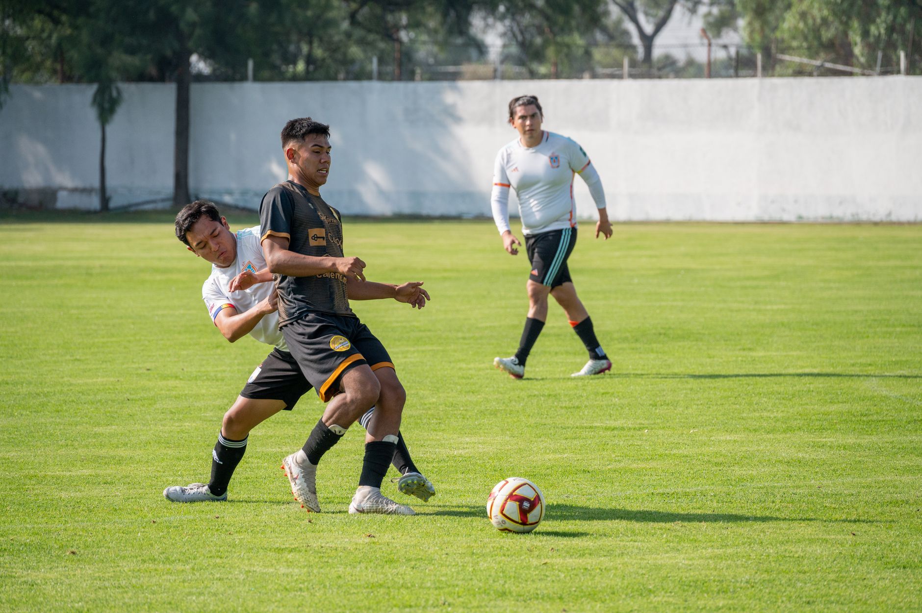 Pemain dalam pertandingan sepak bola yang intens, menunjukkan kerja sama tim dan keterampilan di lapangan hijau.