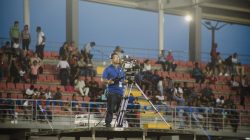 Kamerawan di platform mengambil cuplikan di acara stadion yang ramai.