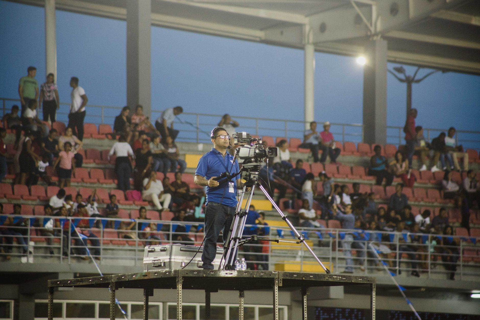 Kamerawan di platform mengambil cuplikan di acara stadion yang ramai.