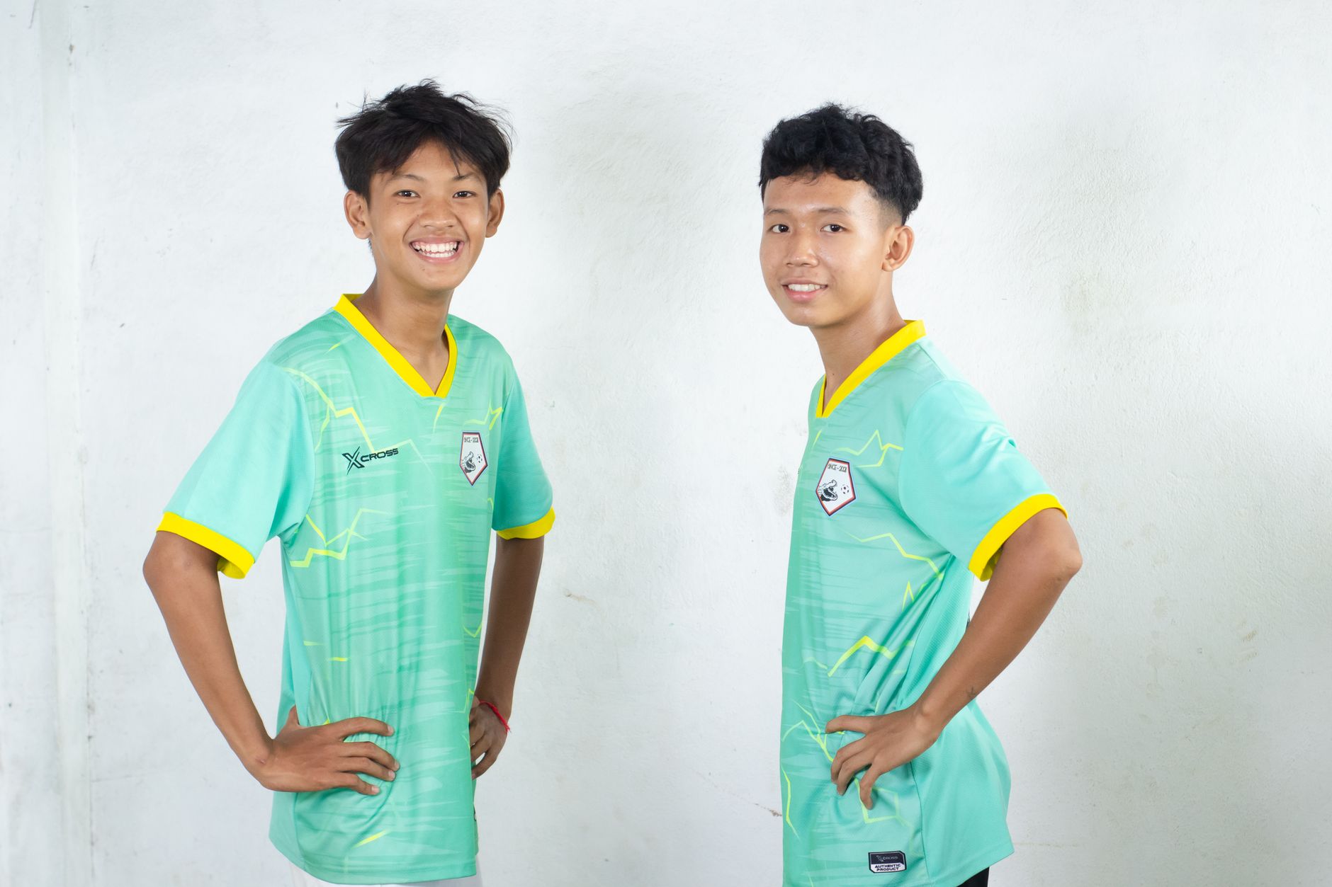 Para pemain sepak bola muda tersenyum dan berpose dengan percaya diri di dalam ruangan.
