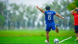 Pemain sepak bola yang energik menendang bola di lapangan hijau di Hanoi, Vietnam.