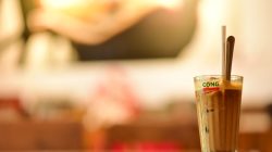 Kopi es yang menyegarkan disajikan dalam gelas dengan sedotan dan sendok di kafe Vietnam yang nyaman.